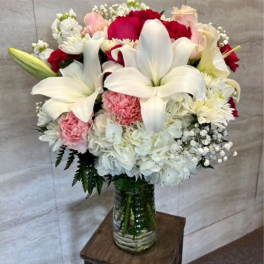 Bouquet of white lilies, red and pink flowers in a glass vase