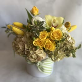 Yellow roses and lilies in a striped ceramic vase