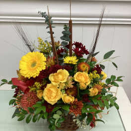 Basket arrangement of yellow roses and red chrysanthemums with tall reeds