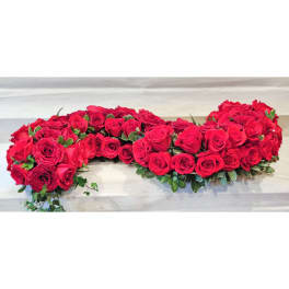 Heart-shaped arrangement of red roses with greenery
