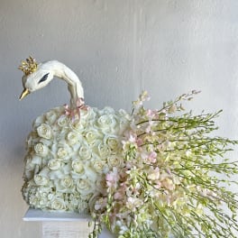 White rose arrangement shaped like a swan with pink orchid sprays