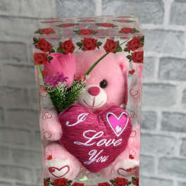 Pink teddy bear in a clear gift box with a heart-shaped "I Love You" decoration