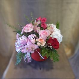 Mixed bouquet in a red hatbox with pink, red, and white flowers