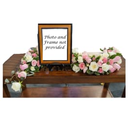Pink and white rose arrangements flanking a framed sign on a table