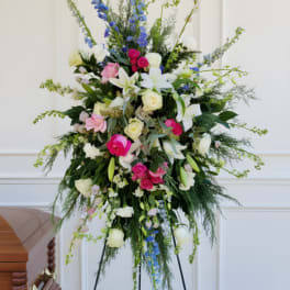 Tall standing floral spray with pink, white, and blue blooms on a black easel