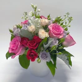 Mixed pink and lavender roses in a white vase