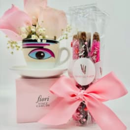 Pink petals in a decorative cup beside a wrapped gift with a bow