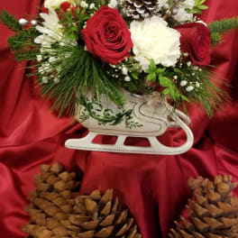 Red and white floral arrangement in a white sleigh container