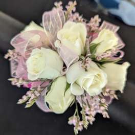 Small corsage of white roses with tiny pink flowers and pink ribbon