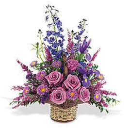 Pink roses and purple flowers arranged in a wicker basket