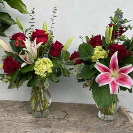 Two bouquets of red roses and pink lilies in glass vases