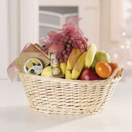 Fruit basket with bananas, grapes, oranges, and packaged sweets in a wicker basket