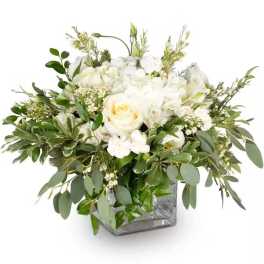 White rose arrangement in a square glass vase with mixed greenery
