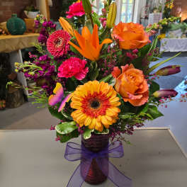 Colorful mixed bouquet in a purple vase with a ribbon