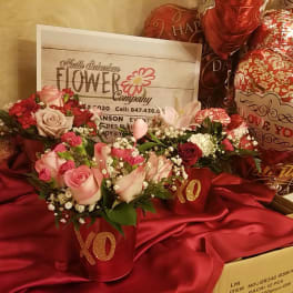Pink and red rose arrangements in red XO containers with heart balloons