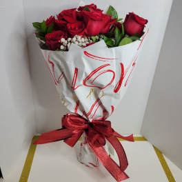 Bouquet of red roses with white filler flowers wrapped in white paper and a red ribbon