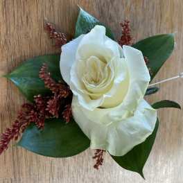 White rose boutonniere with dark green leaves and red filler flowers