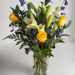Yellow roses and white lilies in a clear glass vase