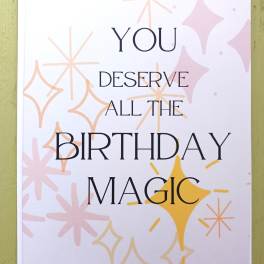 Birthday card with text 'You deserve all the birthday magic' and pastel starburst shapes on a white background