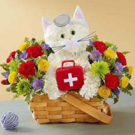 White cat-shaped floral basket with colorful flowers and a red first-aid kit