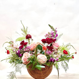 Basket arrangement of pink and red roses with purple flowers