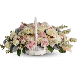 Basket arrangement of pink and cream roses with white blooms