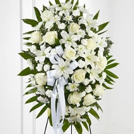 White floral standing spray with roses and lilies on an easel