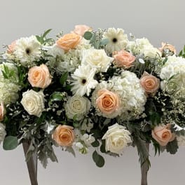 Large floral arrangement of peach and white roses with white blooms