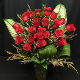 Bouquet of red roses with broad green leaves in a glass vase