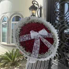 Large round bouquet of red roses with a white lace bow