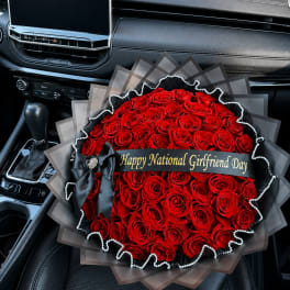 Large bouquet of red roses with a black ribbon and gift banner in a car seat