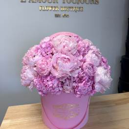 Pink peonies and hydrangeas arranged in a pink hat box