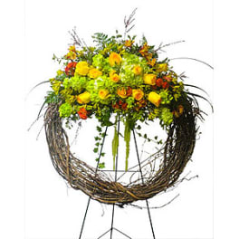 Yellow and orange floral arrangement in a twig wreath stand