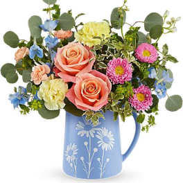 Bouquet of pink roses, blue flowers, and daisies in a blue pitcher vase