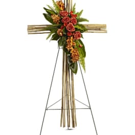 Floral cross on an easel with red roses and greenery