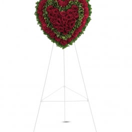 Heart-shaped floral wreath of red roses and carnations on a stand
