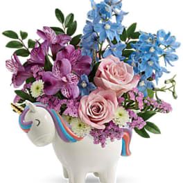 Pink and blue flowers arranged in a unicorn-shaped vase