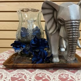 Silver elephant figurine beside a glass vase with dark blue flowers