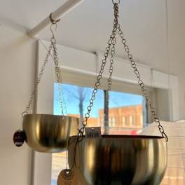 Two gold hanging planters suspended from chains indoors
