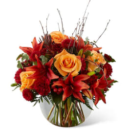 Orange roses and red lilies in a clear glass vase