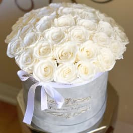 Round bouquet of white roses in a white hatbox with a ribbon