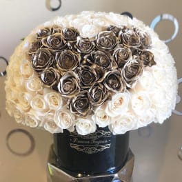 Heart-shaped rose arrangement in a black hatbox on a mirrored stand