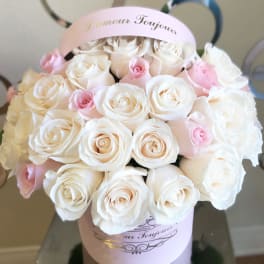 Bouquet of white and pale pink roses in a pink hatbox