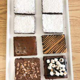 Assorted decorated chocolate brownies arranged on a white tray