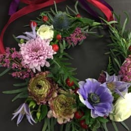 Floral wreath with purple, pink, and white blooms on a dark background