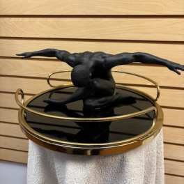 Black sculptural figure on a round mirrored table with gold rails