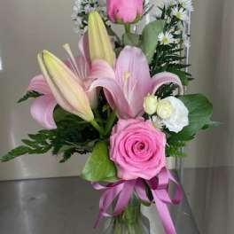 Pink roses and lilies arranged in a clear glass vase