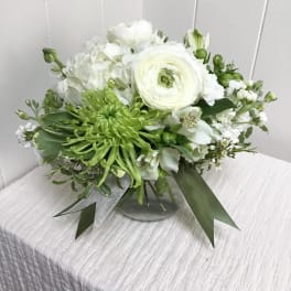 White and green floral arrangement in a glass vase