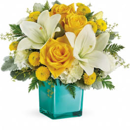 Yellow roses and white lilies in a turquoise glass vase