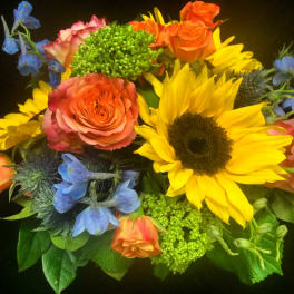 Bright bouquet with yellow sunflower, orange roses, blue delphinium, and green accent blooms
